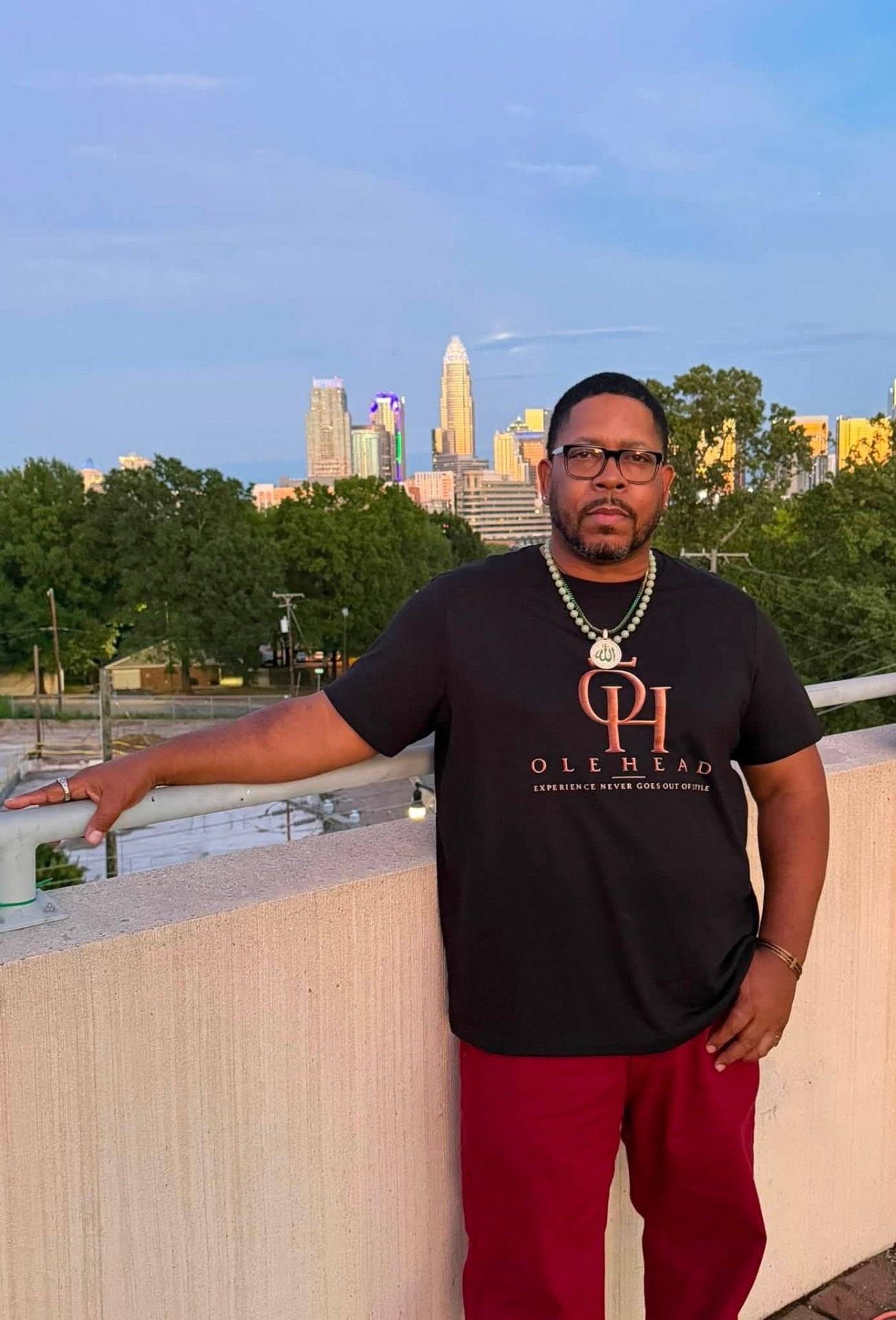 Man wearing the OLE HEAD signature tee in front of the Charlotte skyline